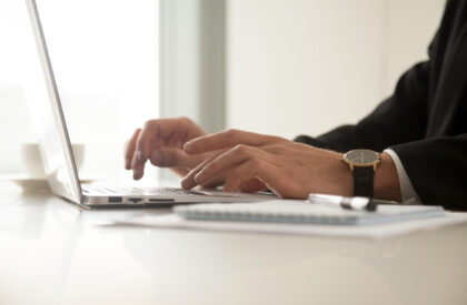 Close up image of mans hands in wristwatch typing on laptop Close up image of guys hands in wristwatch typing on laptop in office. Businessman working on computer at workplace. Office worker browsing internet, communicate online, write blog in social network