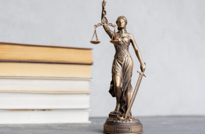 themis goddess of justice statuette, symbol of law with scales and sword in his hands themis goddess of justice statuette on background of books on desktop. symbol of law with scales and sword in his hands. legal company or university of law and judicial structure. library education
